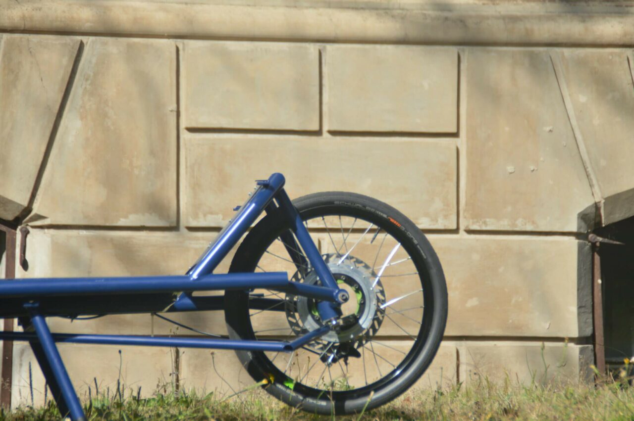 The front wheel of the cargo bike infront of a wall